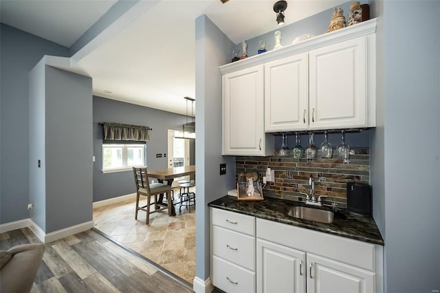 kitchen with decorative backsplash, white cabinetry, sink, and light wood-type flooring