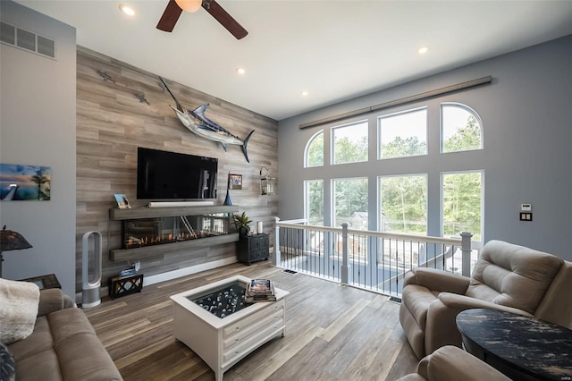 living room featuring hardwood / wood-style flooring, ceiling fan, and wooden walls