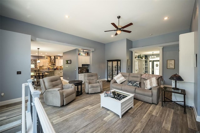 living room featuring ceiling fan with notable chandelier and wood-type flooring