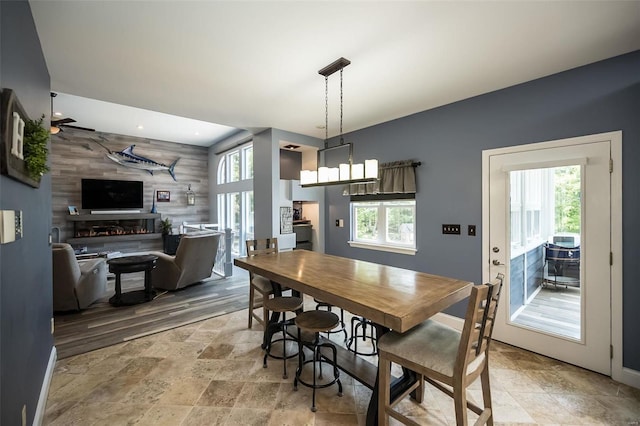 dining space with light wood-type flooring, wooden walls, and a large fireplace