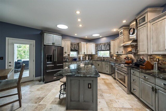 kitchen featuring light tile patterned flooring, a center island, backsplash, wall chimney exhaust hood, and high end appliances