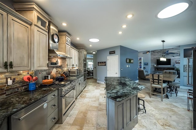 kitchen featuring wall chimney range hood, stainless steel appliances, a center island, light tile patterned floors, and backsplash