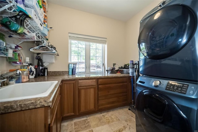 clothes washing area with stacked washer and dryer, light tile patterned floors, cabinets, and sink