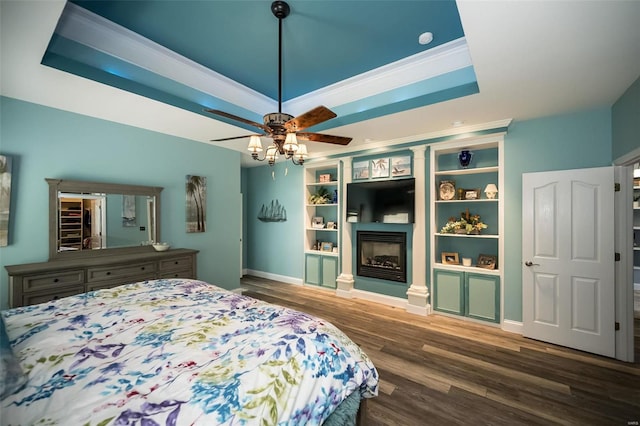 bedroom with ceiling fan, wood-type flooring, ornamental molding, and a tray ceiling