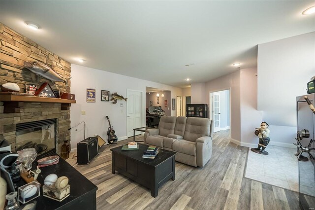 living room featuring a stone fireplace and light wood-type flooring