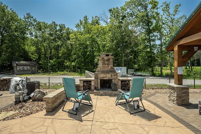 view of patio with an outdoor stone fireplace and a storage shed