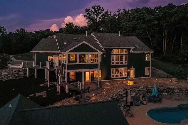 back house at dusk with a patio area and a pool side deck