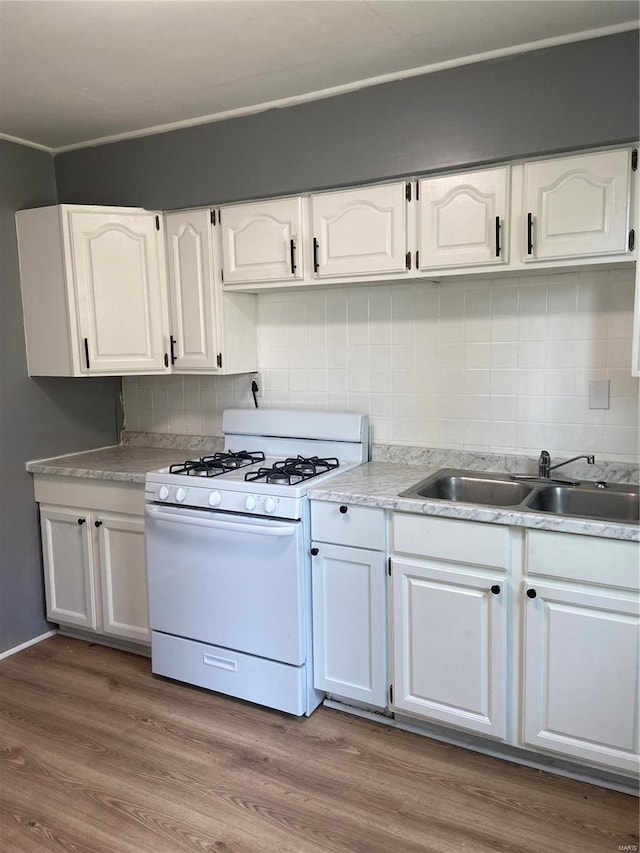 kitchen with sink, hardwood / wood-style floors, tasteful backsplash, white cabinets, and white gas range