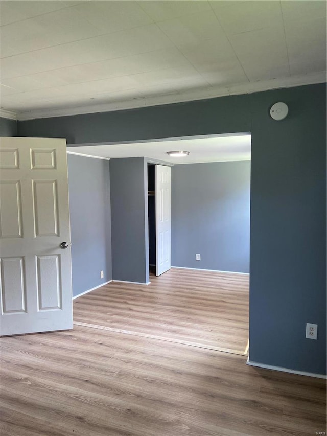 unfurnished room with ornamental molding and light wood-type flooring