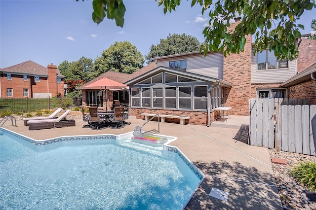 back of property with a patio, a sunroom, and a fenced in pool