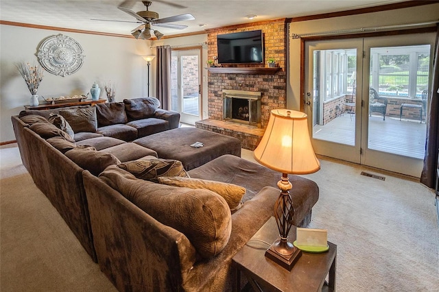 carpeted living room with ceiling fan, brick wall, a brick fireplace, and crown molding