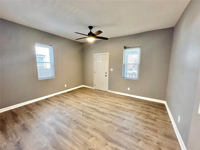 empty room with ceiling fan, light hardwood / wood-style flooring, and a healthy amount of sunlight