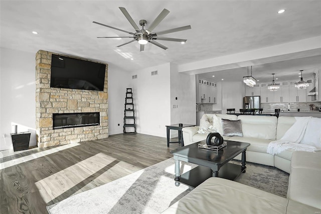 living room with hardwood / wood-style flooring, ceiling fan, and a fireplace