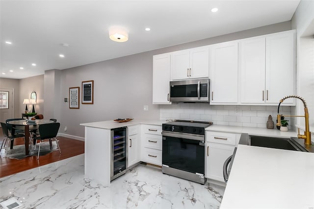 kitchen with appliances with stainless steel finishes, sink, kitchen peninsula, white cabinets, and wine cooler