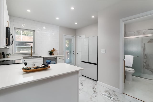 kitchen featuring stainless steel dishwasher, white cabinets, and sink