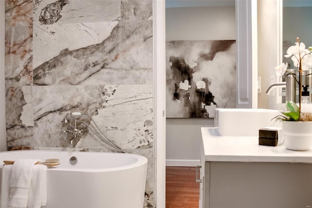 bathroom featuring vanity, hardwood / wood-style flooring, and a bath