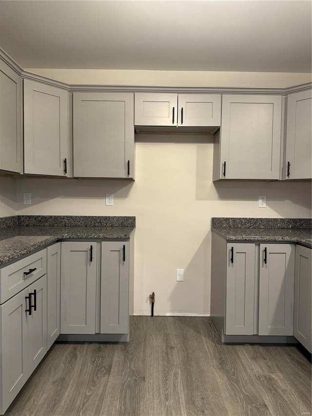 kitchen featuring gray cabinets, dark stone countertops, and dark wood-type flooring