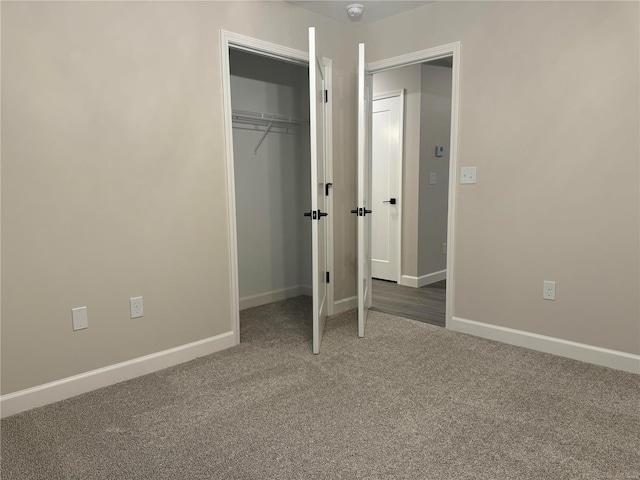 unfurnished bedroom with dark carpet and a closet