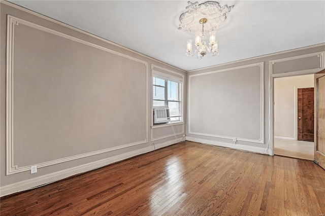 empty room with an inviting chandelier, crown molding, and wood-type flooring