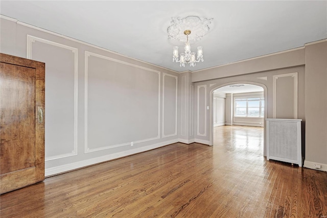 unfurnished room with a notable chandelier and hardwood / wood-style floors