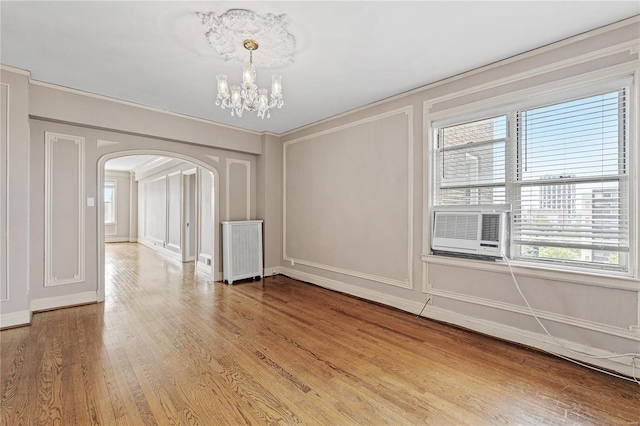 unfurnished dining area with hardwood / wood-style flooring, ornamental molding, radiator heating unit, and an inviting chandelier