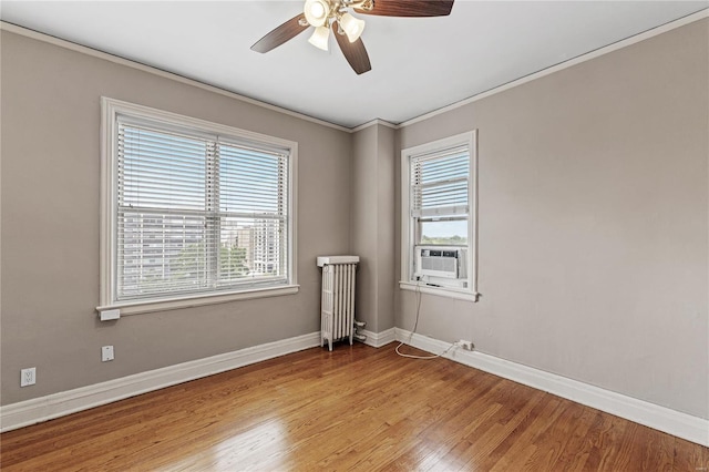 empty room featuring radiator heating unit, cooling unit, ornamental molding, ceiling fan, and light hardwood / wood-style floors