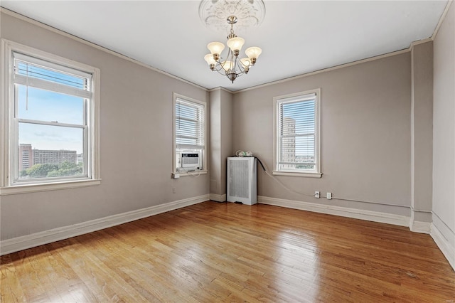 spare room with an inviting chandelier, hardwood / wood-style flooring, ornamental molding, radiator, and cooling unit