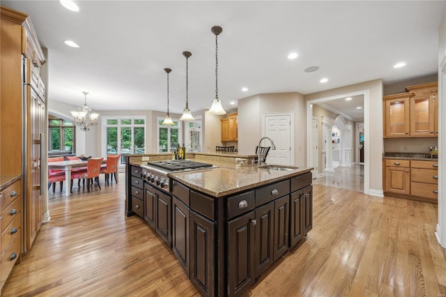 kitchen featuring decorative light fixtures, light wood-type flooring, a large island with sink, and sink