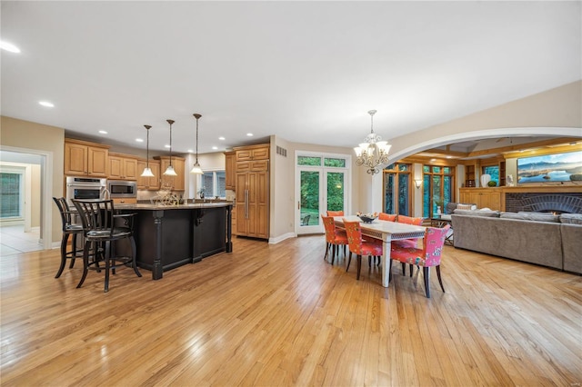 dining area with a brick fireplace, an inviting chandelier, and light hardwood / wood-style floors