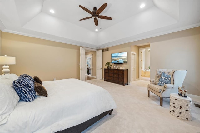 carpeted bedroom with crown molding, a tray ceiling, ceiling fan, and ensuite bathroom