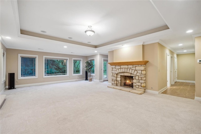 unfurnished living room featuring light carpet, a fireplace, crown molding, and a raised ceiling