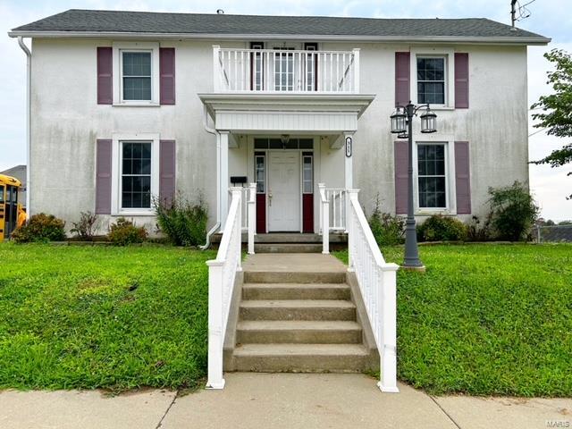 view of front of property featuring a balcony and a front lawn