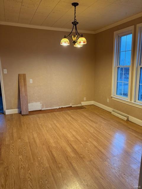 unfurnished room with light hardwood / wood-style floors, an inviting chandelier, and ornamental molding