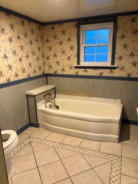 bathroom featuring tile patterned flooring, a washtub, toilet, and ornamental molding