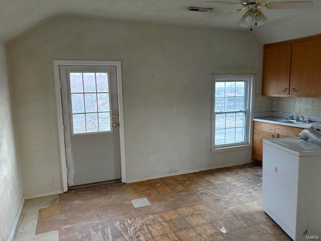 interior space with a healthy amount of sunlight, ceiling fan, cabinets, and washer / dryer