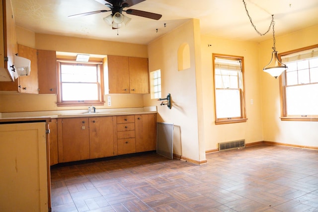 kitchen featuring sink, ceiling fan, and hanging light fixtures