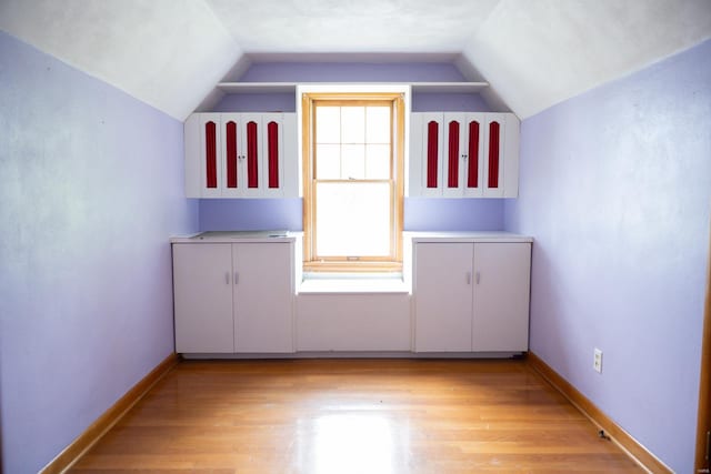 additional living space featuring lofted ceiling and light hardwood / wood-style floors