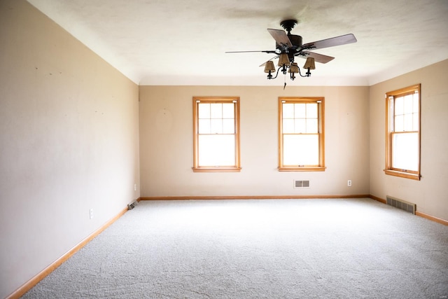 empty room featuring carpet, a healthy amount of sunlight, and ceiling fan