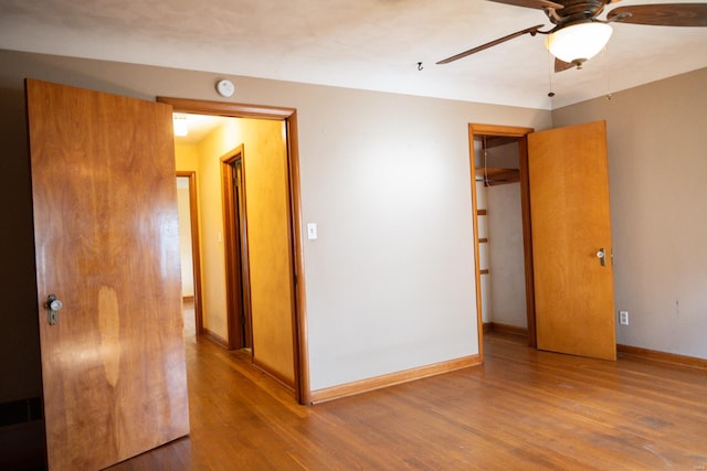 unfurnished bedroom featuring ceiling fan, hardwood / wood-style flooring, a closet, and a spacious closet