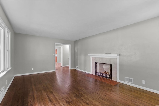 unfurnished living room featuring a tile fireplace and hardwood / wood-style floors