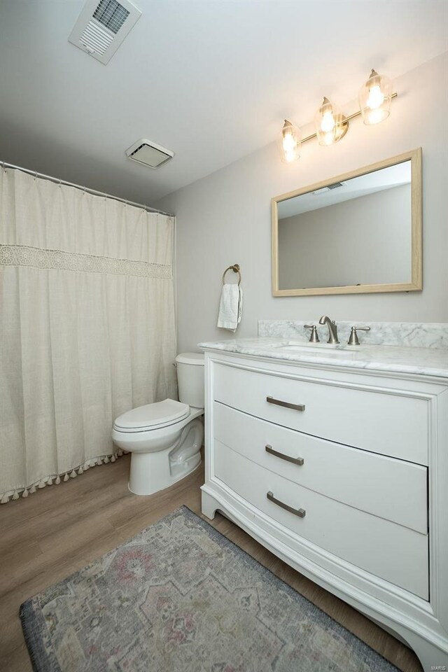 bathroom with wood-type flooring, toilet, and vanity