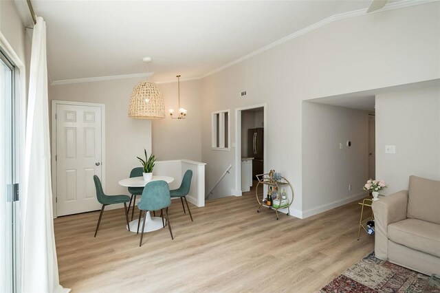 dining room featuring crown molding, an inviting chandelier, vaulted ceiling, and light hardwood / wood-style flooring