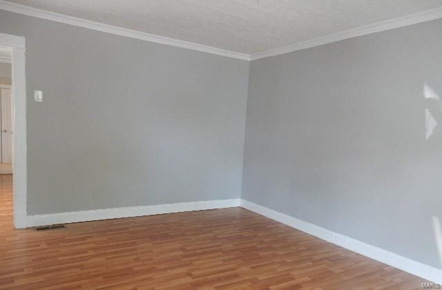 empty room featuring ornamental molding and hardwood / wood-style floors