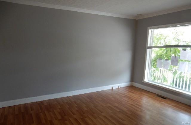 unfurnished room with wood-type flooring, crown molding, and a wealth of natural light