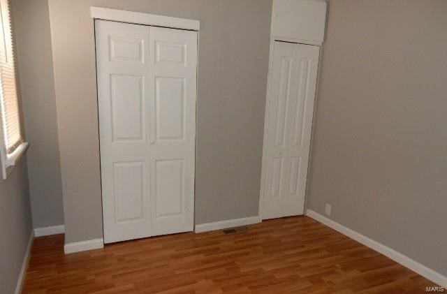 unfurnished bedroom featuring wood-type flooring and a closet