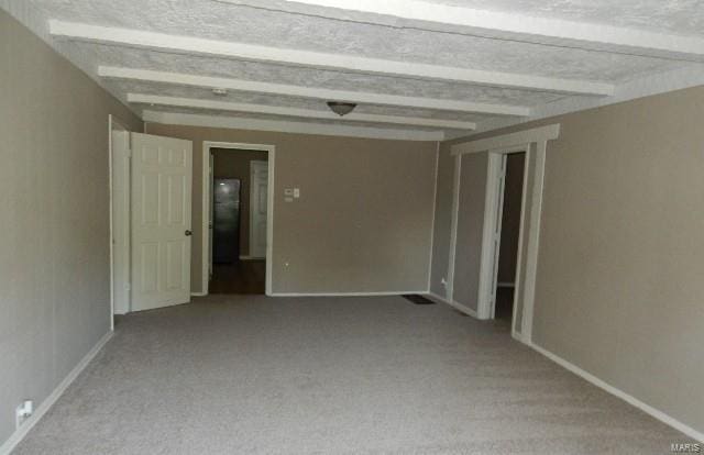 carpeted empty room with beamed ceiling