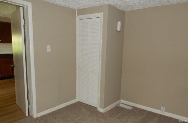 unfurnished bedroom featuring light carpet, a closet, and a textured ceiling