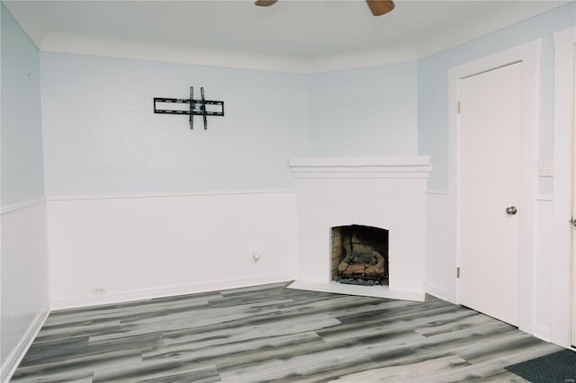 unfurnished living room featuring wood-type flooring, a brick fireplace, and ceiling fan