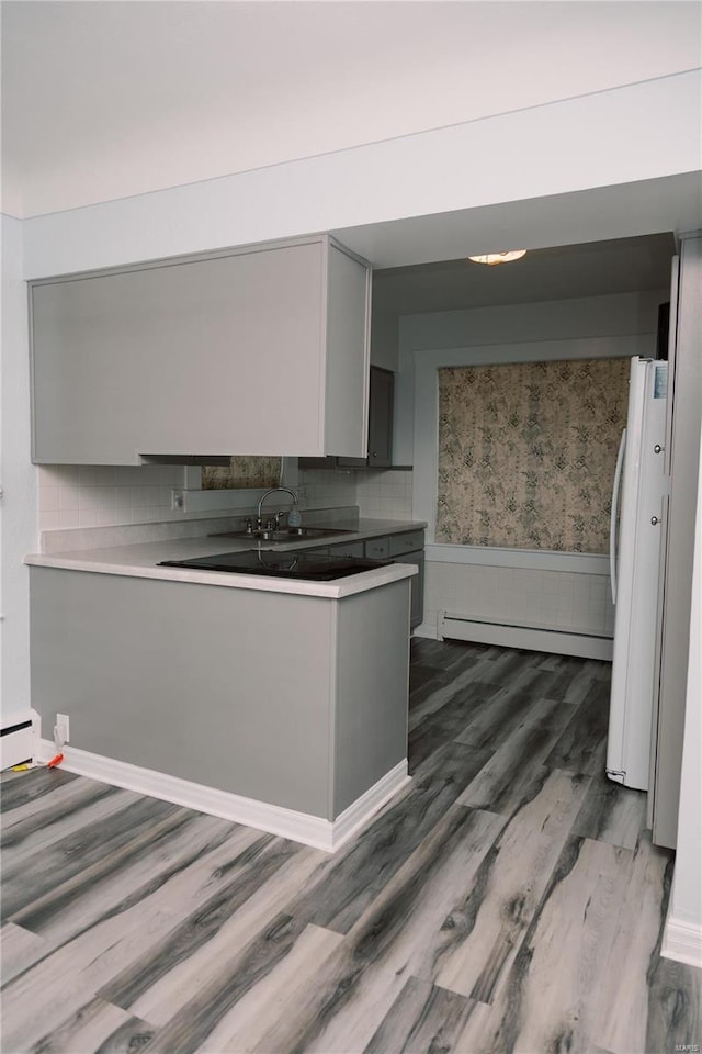 kitchen with white refrigerator, gray cabinetry, dark hardwood / wood-style flooring, sink, and a baseboard radiator