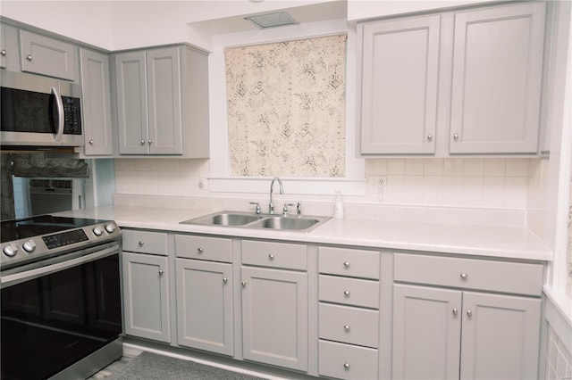 kitchen with gray cabinets, appliances with stainless steel finishes, sink, and tasteful backsplash